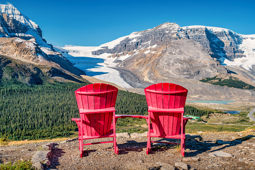 Red Lounge Chairs with Athabasca Glacier and Columbia Icefield in the background in the Canadian Rockies, Alberta, Canada.