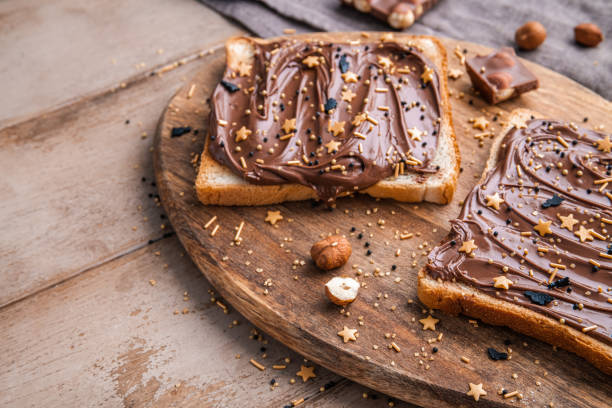 istock Board of bread with chocolate paste and hazelnuts on wooden background 1438988900