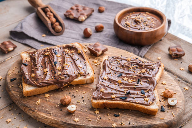 istock Board of bread with chocolate paste and hazelnuts on wooden background 1438988958