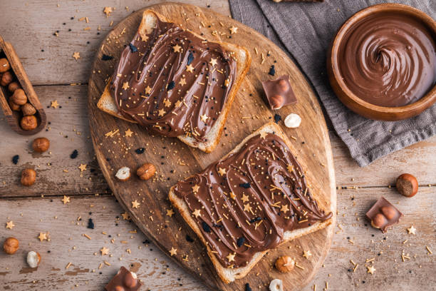 istock Board of bread with chocolate paste and hazelnuts on wooden background 1438989023