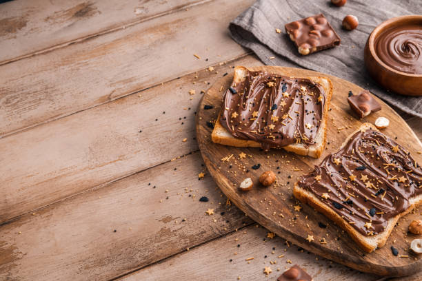istock Board of bread with chocolate paste and hazelnuts on wooden background 1438989032