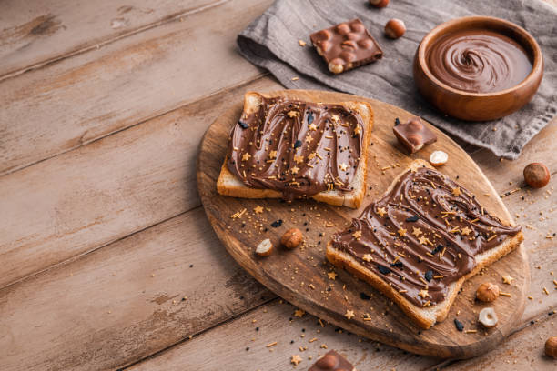 istock Board of bread with chocolate paste and hazelnuts on wooden background 1438989047