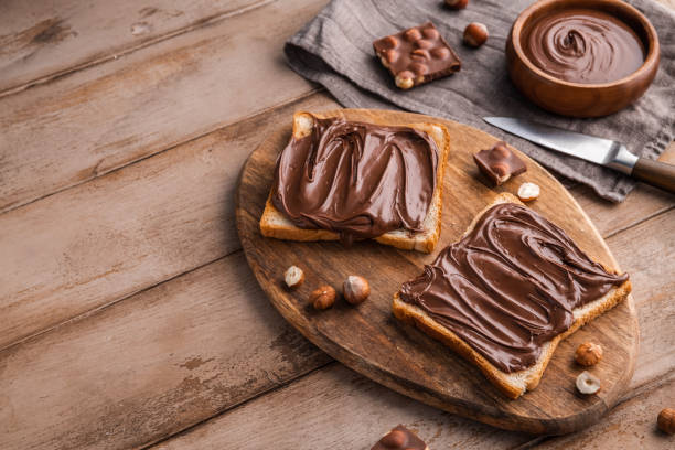 istock Board of bread with chocolate paste and hazelnuts on wooden background 1438989063