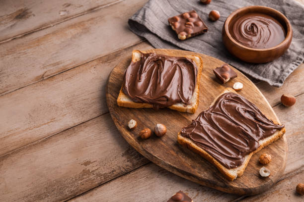 istock Board of bread with chocolate paste and hazelnuts on wooden background 1438989081