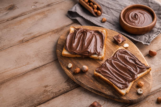 istock Board of bread with chocolate paste and hazelnuts on wooden background 1438989112
