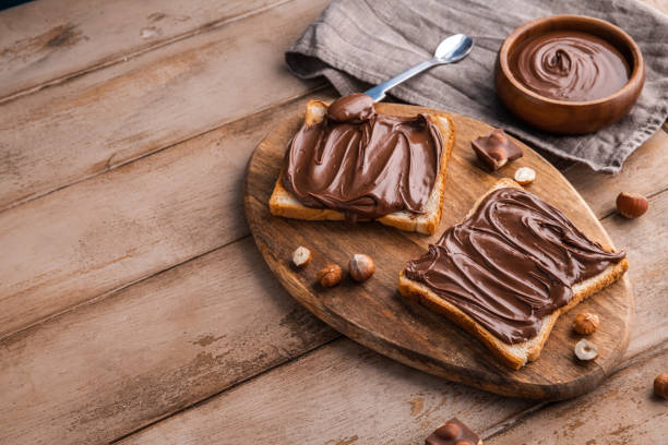 istock Board of bread with chocolate paste and hazelnuts on wooden background 1438989137