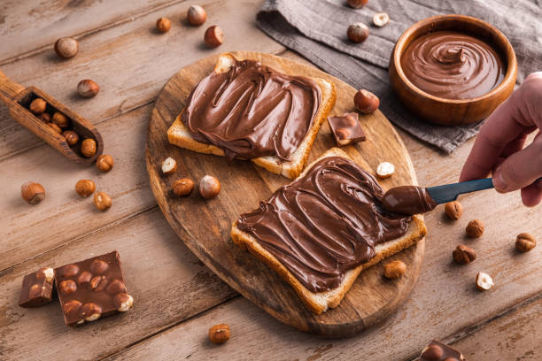 istock Board of bread with chocolate paste and hazelnuts on wooden background 1438989166