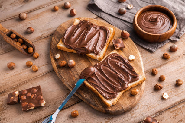 istock Board of bread with chocolate paste and hazelnuts on wooden background 1438989197