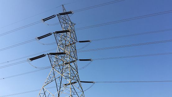 Electricity transmission pylon silhouetted against blue sky