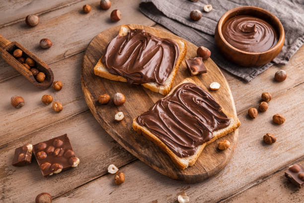 istock Board of bread with chocolate paste and hazelnuts on wooden background 1438989246