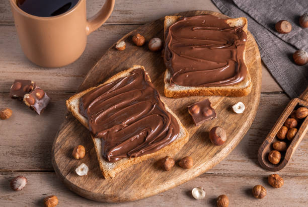 istock Board of bread with chocolate paste and hazelnuts on wooden background 1438989283