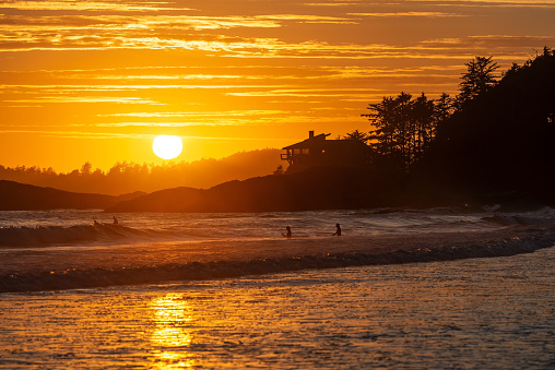 Sunset by Chesterman Beach with surfers in the Pacific Ocean, Tofino, British Columbia, Canada.