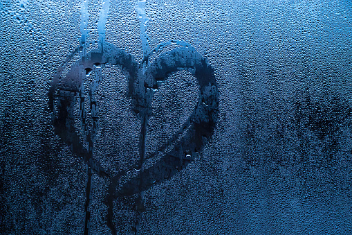 Heart painted on misted glass. Valentines day, love symbol on frozen glass in winter. Selective focus.