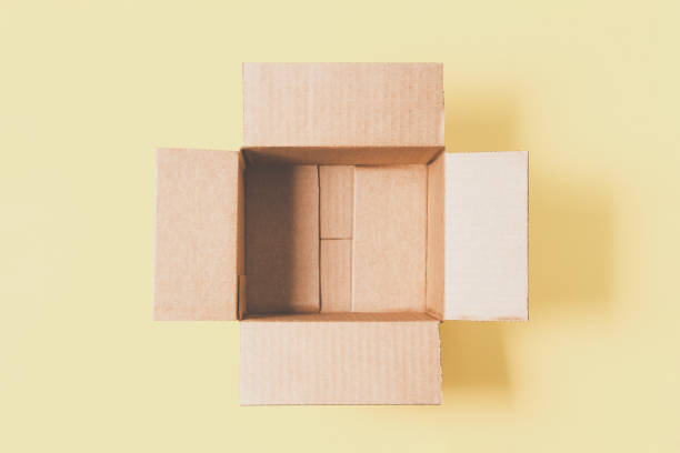 istock One empty open cardboard box on pastel yellow background. Top view, copy space 1438992869