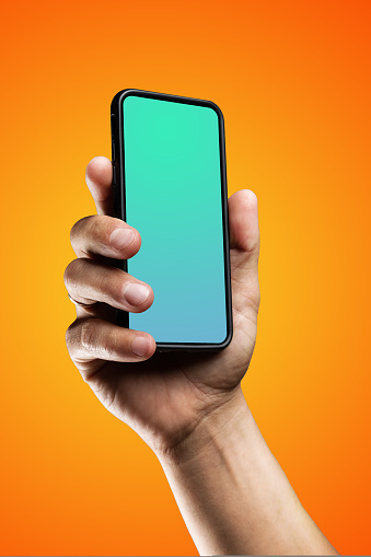 Modern smartphone in black case with a screen template in the man's hand. Isolated on orange color background