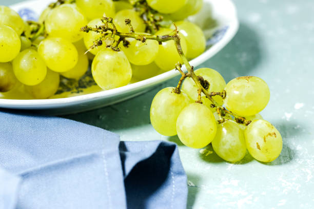 Green grape in antique white plate on wooden table