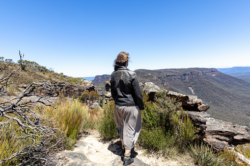 Young woman standing and looking over mountains valley, Blue Mountains National park, background with copy space, full frame horizontal composition