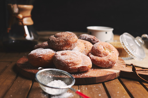 Snake doughnuts with powdered sugar and chemex coffee on a wooden table