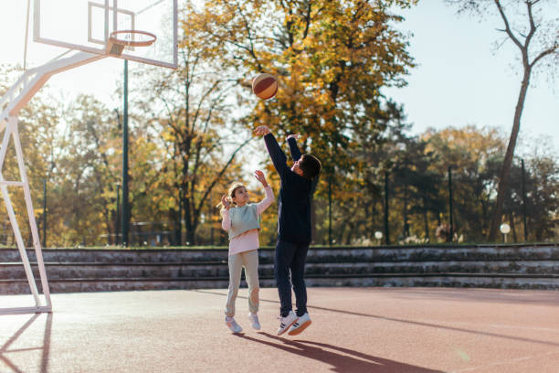 istock Two children playing basketball outdoors 1439006331