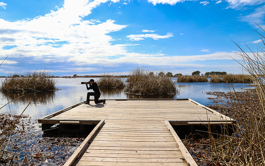 Mandeville, Louisiana, United States – February 06, 2018: Fontainebleau State Park, Louisiana - February 2018: A young male photographer on the observation platform on the Alligator Marsh Boardwalk.