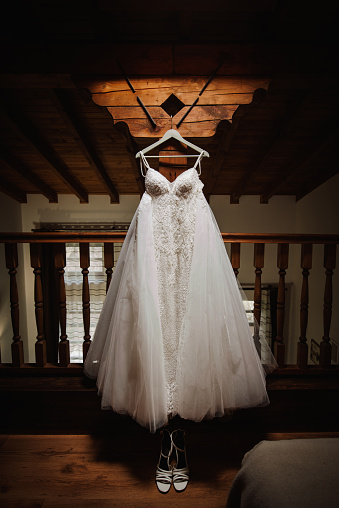 Elegant wedding dress on a a hanger and bride's shoes