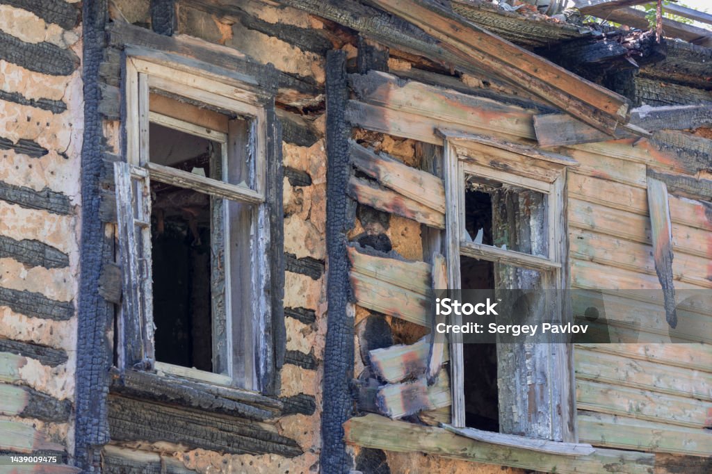 two windows in a burnt house Facade of a wooden burnt house with two windows Abandoned Stock Photo