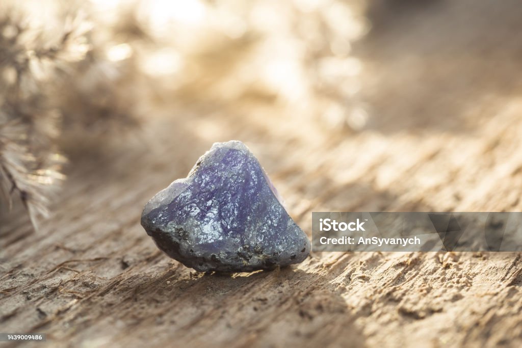 Rough Uncut Blue and Violet Tanzanite Gem on Wood Rough Uncut Blue and Violet Tanzanite Gem on Wooden Background. Tanzanite is the most Valuable Gemstone Tanzanite Stock Photo