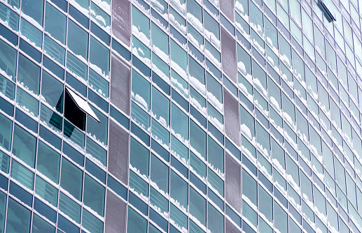 Winter glass blue wall building skyscrapers with snow and one opened window. Electricity saving concepts