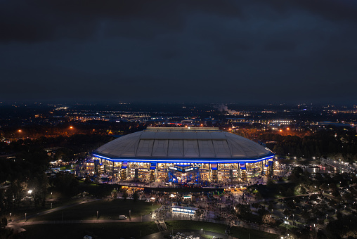 Gelsenkirchen, Ruhr, Germany - October 2022: Arial panoramic night view on the illuminated Veltins Arena (Arena AufSchalke), home stadium for Bundesliga team FC Schalke 04