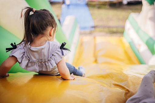 Cute little girl playing in inflatable bouncy castle in amusement park.