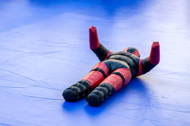 Red black punching bag mannequin two-legged wrestling blue sports hall background. Sport gear concept. Red black punching bag mannequin two-legged wrestling blue sports hall kickboxing ring background. Sport equipment concept. wrestlers uniform stock pictures, royalty-free photos & images