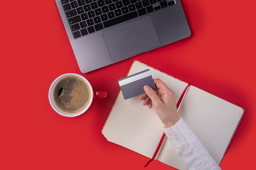 Woman holding credit card in front of the laptop. Shopping online concept
