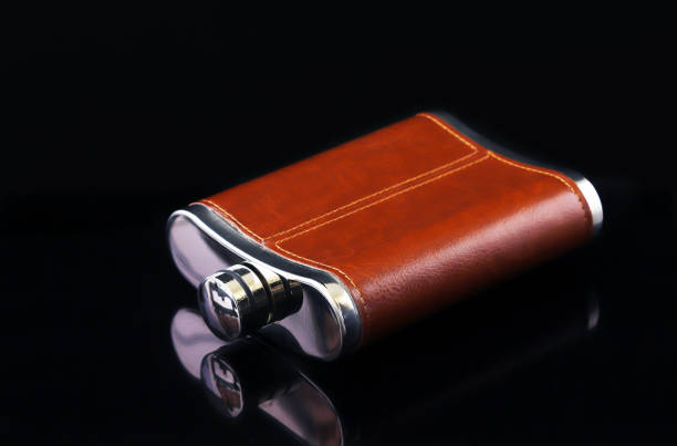 istock Alcoholic flask in leather trim on a black background with reflection. Close-up 1439018269