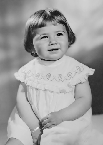 Image taken in late 50s, little girl posing holding a phone looking at the camera