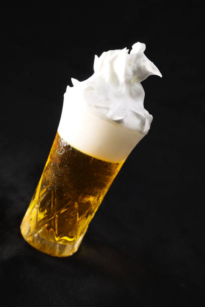 Beer foam overflowing from glass isolated on a black background. stock photo
