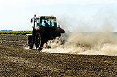 Farmer in a Tractor is Plowing a Field.