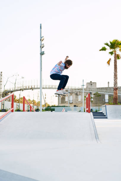 istock Bearded tricker jumping on skateboard in skate park 1439034741