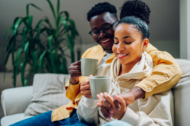 istock Multiracial couple relaxing on a couch at home and drinking coffee 1439038114