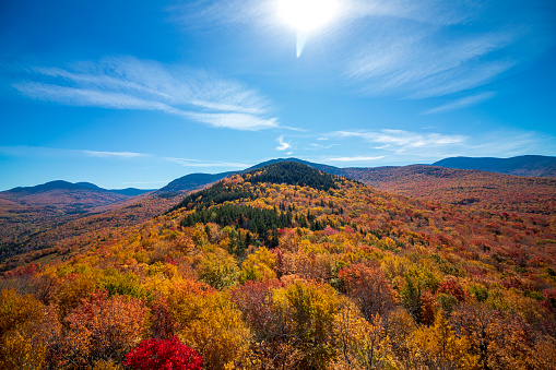 Peak foliage in the White Mountain National Forest looking out towards Mount Washington which is partially snowcapped.