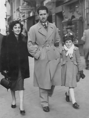 Black and white Image taken in early 50s:Young couple walking with their daughter