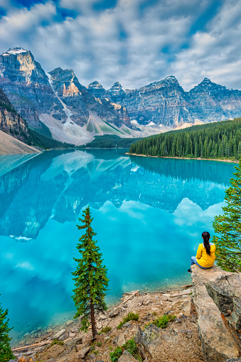 Woman looks at the view at Moraine Lake, Canadian Rockies, Alberta, Canada in the morning.