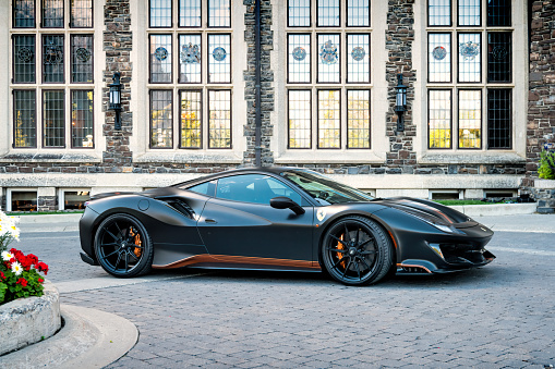 A black colored Ferrari 488 Pista luxury coupe is parked on the street at the Fairmont Banff Springs Hotel in Banff, Alberta, Canada on a sunny day.