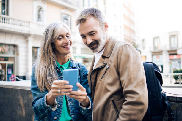 istock Happy mature couple on vacation walking and using smartphone 1439052698