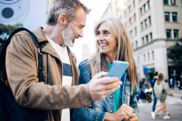 istock Happy mature couple on vacation walking and using smartphone 1439052699