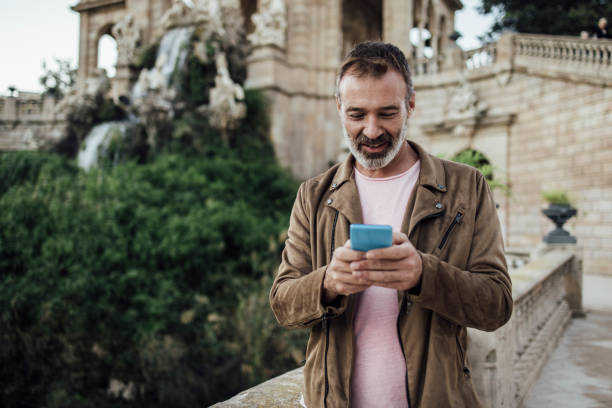 istock Mature tourist using phone while walking through Barcelona 1439052744