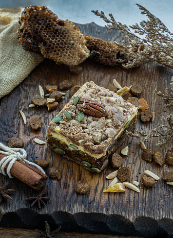 Homemade spiced pumpkin cream cheese chinnamon cake bars frosting decorated with pecan nuts and pistachio sliced into squares served on rustic wooden background. The concept of delicious dessert, Selective Focus.