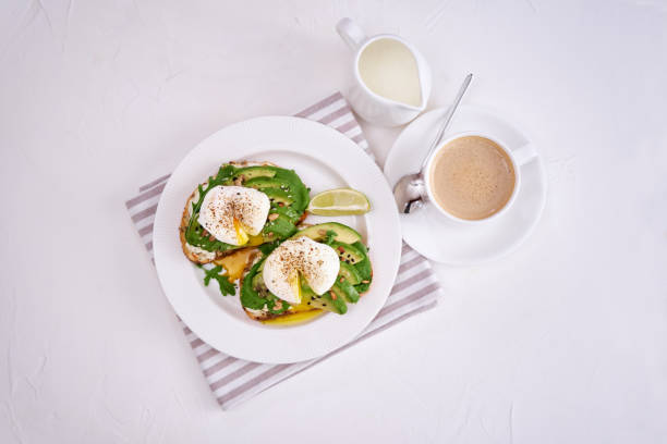 istock Freshly made poached egg and Avocado toasts on light grey background 1439062404