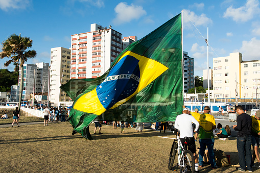 Salvador, Bahia, Brazil - October 22, 2022: Supporters of the President of Brazil Jair Bolsonaro, protest by placing a large Brazilian flag in Farol da Barra square in Salvador.