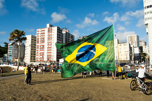 Salvador, Bahia, Brazil - October 22, 2022: Supporters of the President of Brazil Jair Bolsonaro, protest by placing a large Brazilian flag in Farol da Barra square in Salvador.