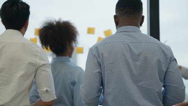 istock Post-it notes on glass board, Businesspeople taking colorful reminder post-it notes on board during conference with business team in the meeting room, Teamwork meeting 1439097234